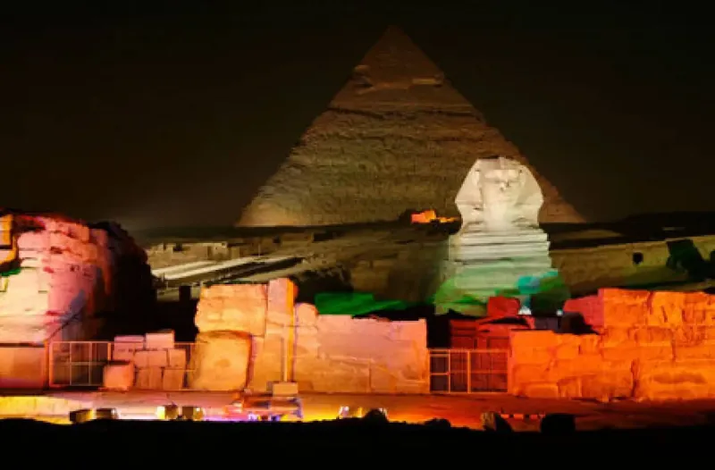 Great Sphinx of Giza illuminated at night Sound and Light Show Egypt — face and pyramid lit gold against dark sky