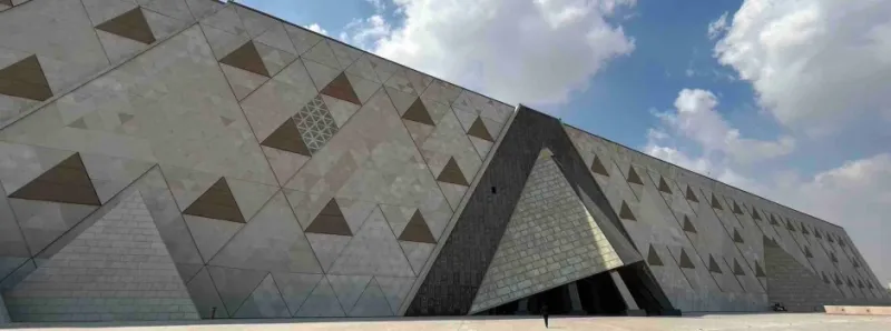 Grand Egyptian Museum GEM exterior at night with Pyramids of Giza visible behind Giza Egypt 2026
