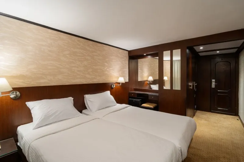 Nile Commodore standard cabin — panoramic Nile view window, private en-suite shower bathroom, AC, TV, mini bar and safe, classic 5-star Egypt 2026